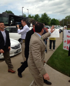 Jones says hello to Medicaid protesters before walking into one of his events. (Photo by Collin Reischman)