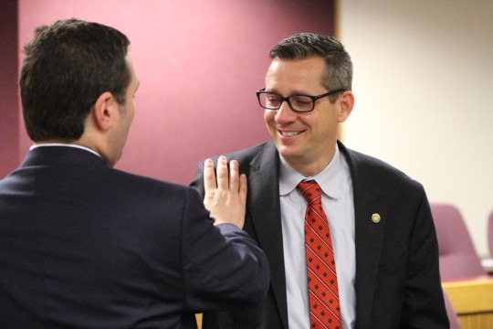 Rep. Mike Colona (left) pats Rep. Ron Hicks' shoulder after the committee vote on SJR 39.